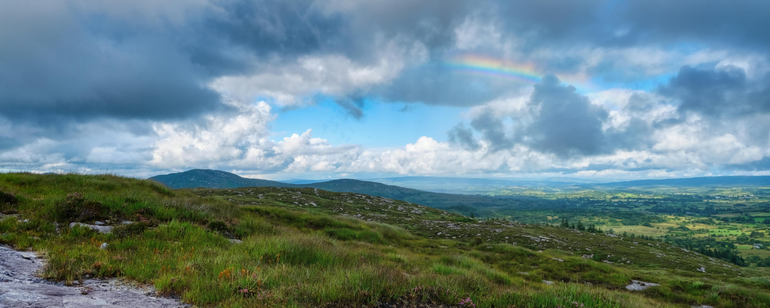 Rolling Irish hills with a rainbow in the sky