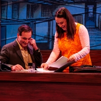 A man and a woman at a desk looking at a folder and smiling