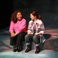 Two women sitting facing each other, smiling.