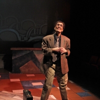 Photo of a man standing next to a brief case looking up and talking to someone
