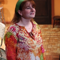 Woman in an orange shirt looking off and smiling