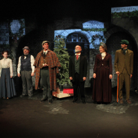 Six people in Victorian dress standing in front of a Christmas tree