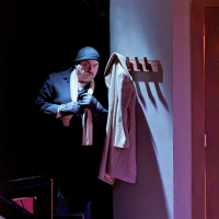 A man lurking in the dark holding a knotted scarf