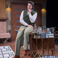 A man sitting on the edge of a desk, talking on the phone