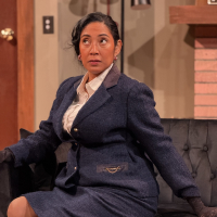 A woman in a dark suit sitting on a couch