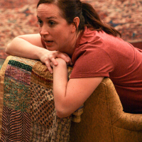 A woman leaning over the back of a chair resting on her arms