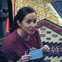 A woman holding an index card with writing on it, smiling out