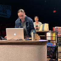 A woman working at a computer with another woman behind her looking over her shoulder