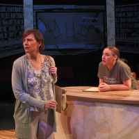 Two women standing at a counter, one looking off the other looked at the first one