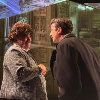 A man in a wig talking to another man