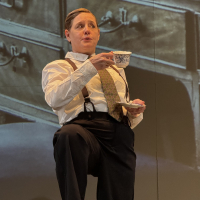 A woman dressed as a man with her leg on a table, holding a tea cup