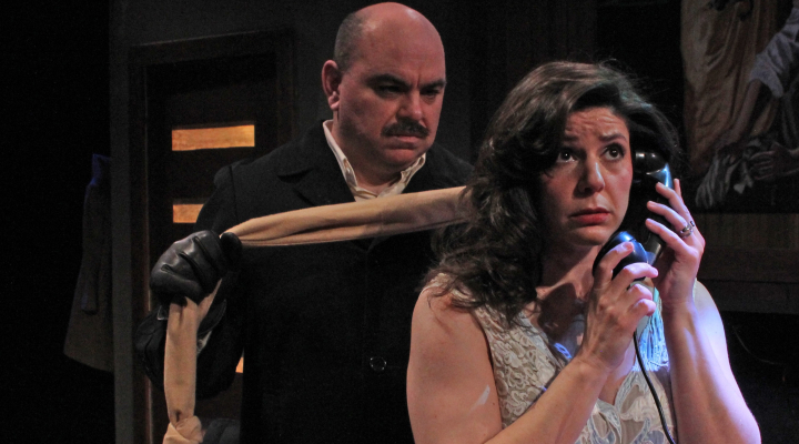 A man with a scarf sneaking up on a woman who is talking on the telephone