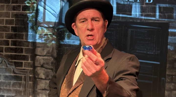 A man in a top hat holding a blue stone out in front of him