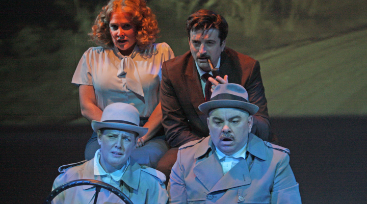 Four people looking unhappy driving in a car with an exterior background projected behind them.