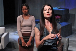 One woman looking off in the distance, another woman standing behind her looking at her.